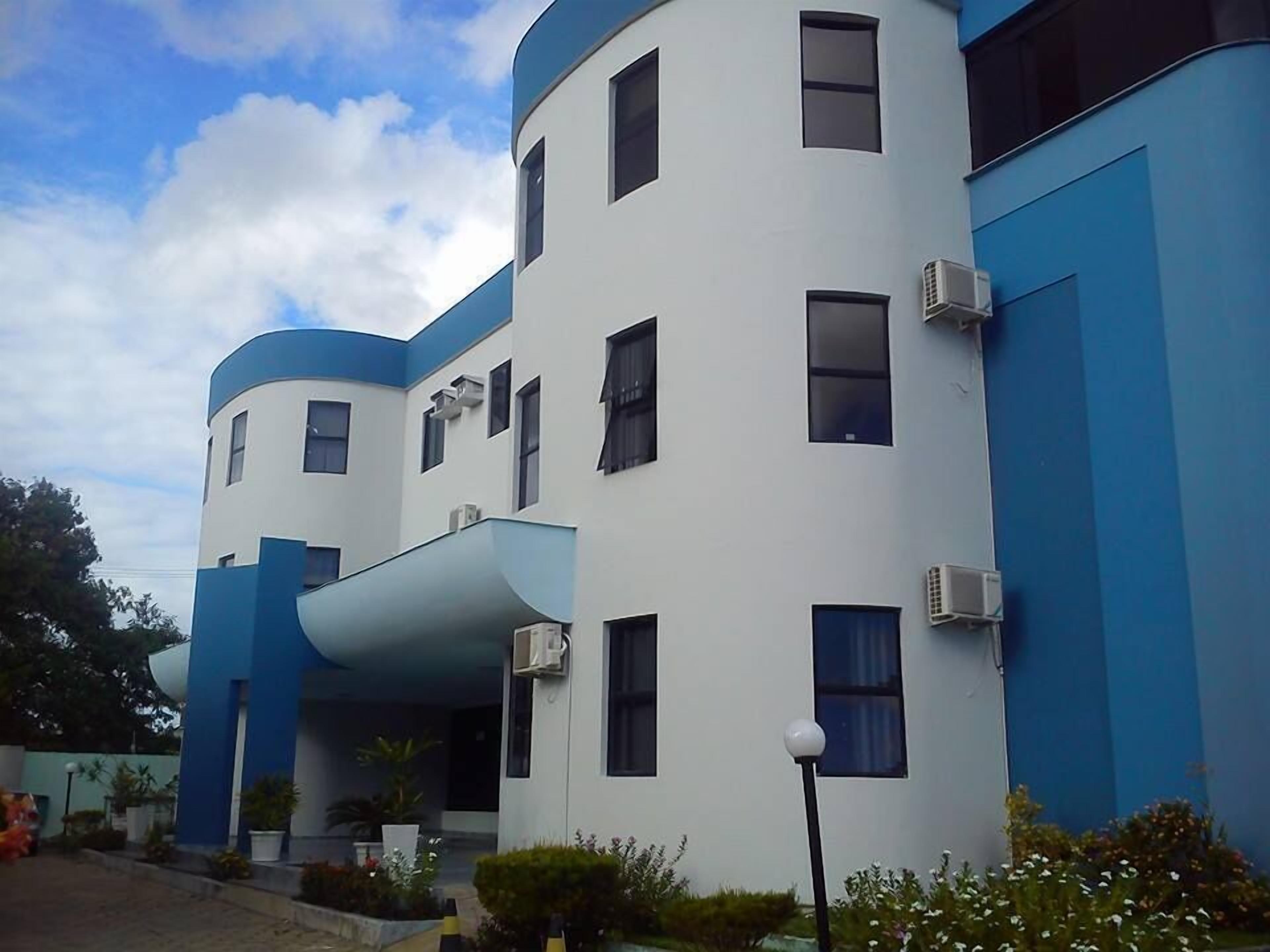 A modern building with a curved facade, multiple windows, and air conditioning units.