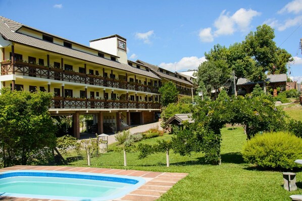 A hotel with a pool, multiple balconies, and a garden area. - Pousada dos Plátanos (Nova Petropolis)