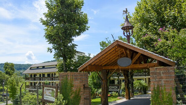 A wooden pavilion with a brick entrance, surrounded by greenery and a signboard. - Pousada dos Plátanos (Nova Petropolis)
