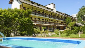 A hotel with a pool, multiple balconies, and lush greenery. - Pousada dos Plátanos (Nova Petropolis)