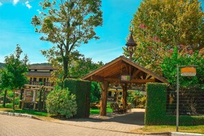 A wooden gazebo with a sign, surrounded by greenery and a paved path. - Pousada dos Plátanos (Nova Petropolis)