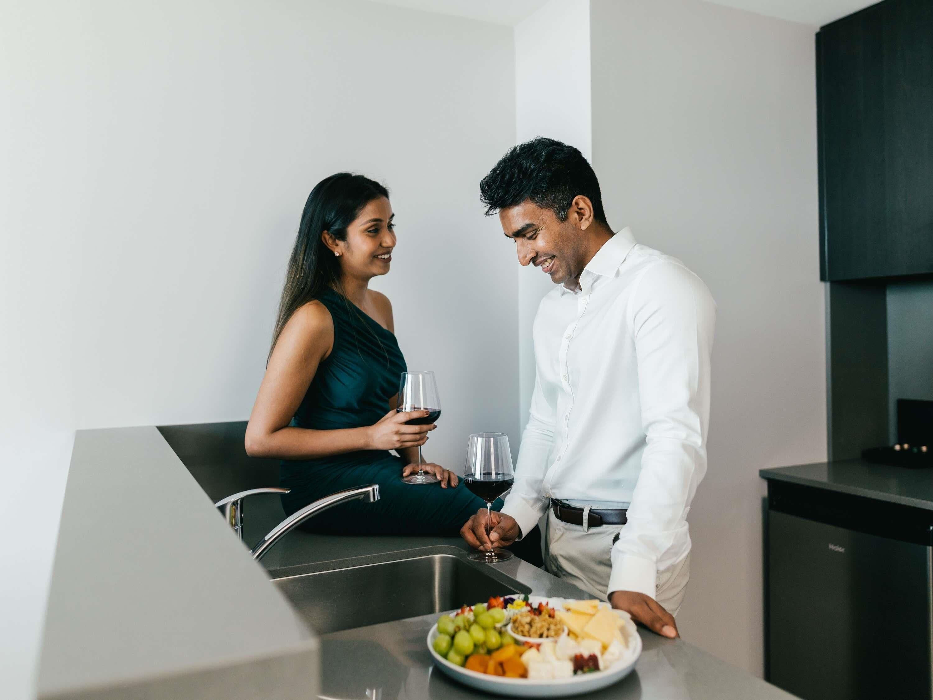 Una cocina moderna con un lavamanos de acero inoxidable, una mesa de comedor con un plato de comida y una persona con una camisa blanca.
