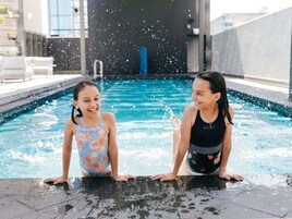 Two individuals at a swimming pool with water splashing around them.
