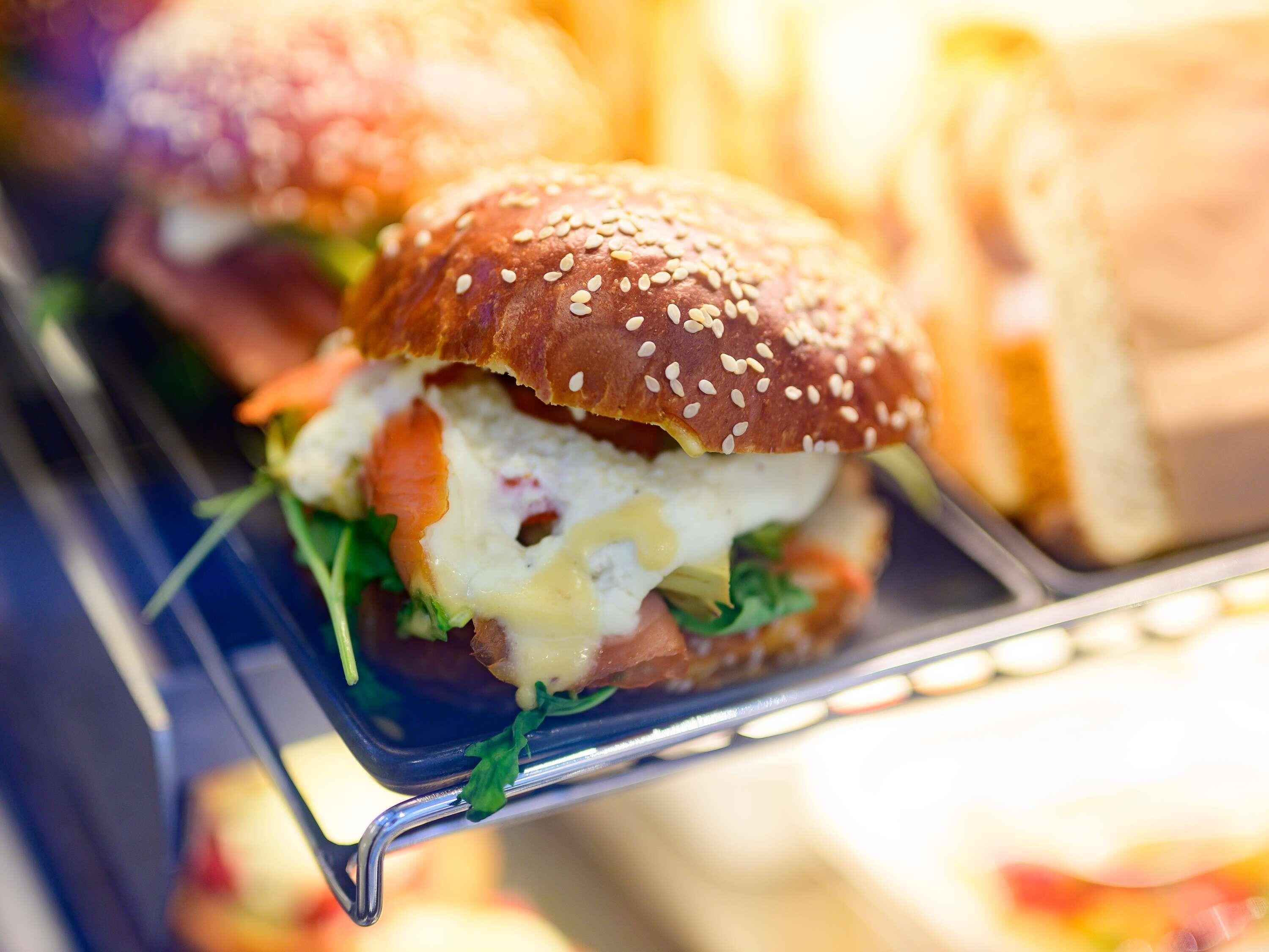 A sandwich with sesame seeds on the bun, lettuce, and melted cheese.