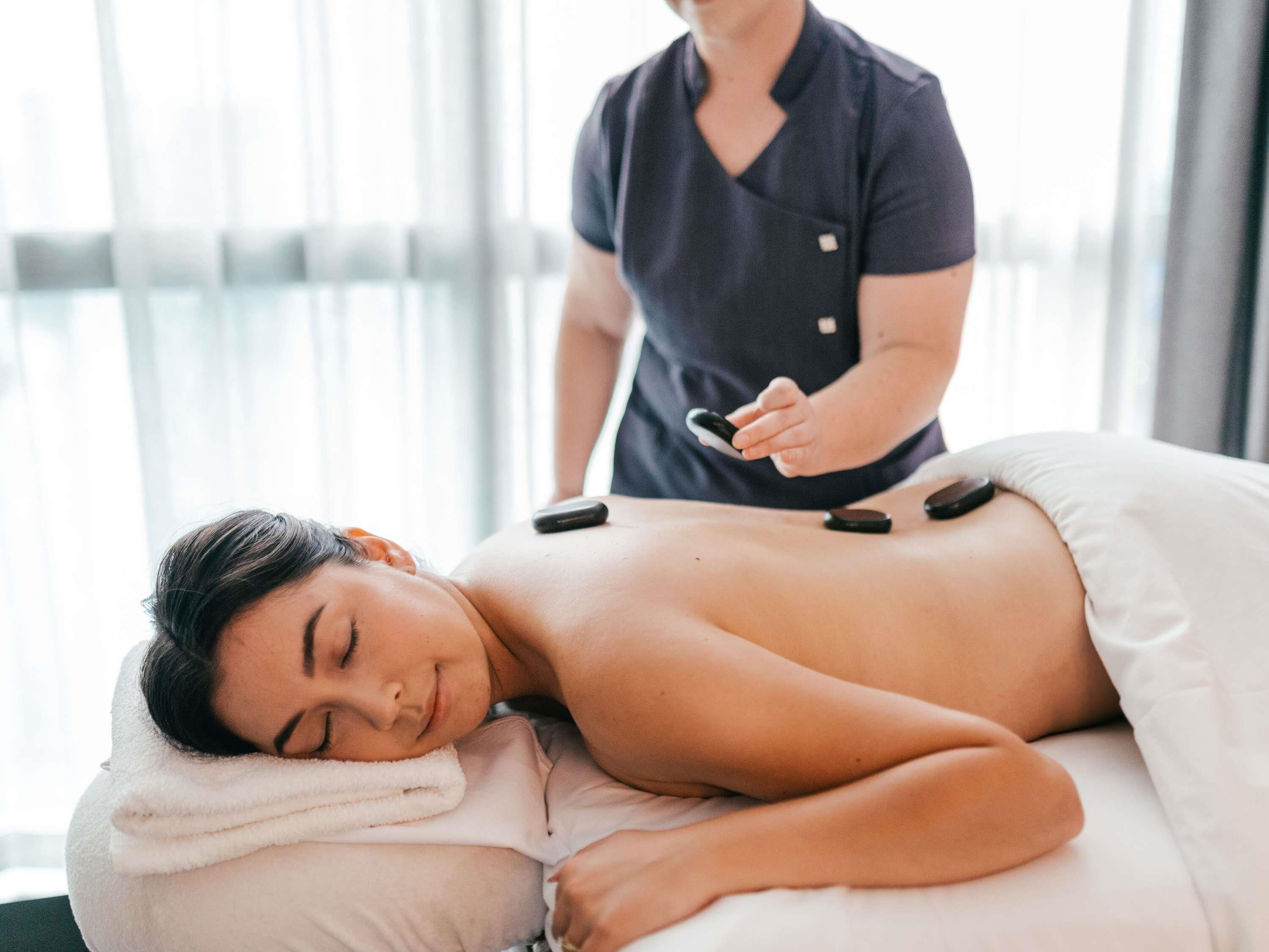 A person lying on a massage table receiving a back treatment.