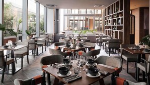 A modern restaurant with tables set for dining, large windows, and a view of greenery outside. - Novotel Perth Murray Street (Perth)