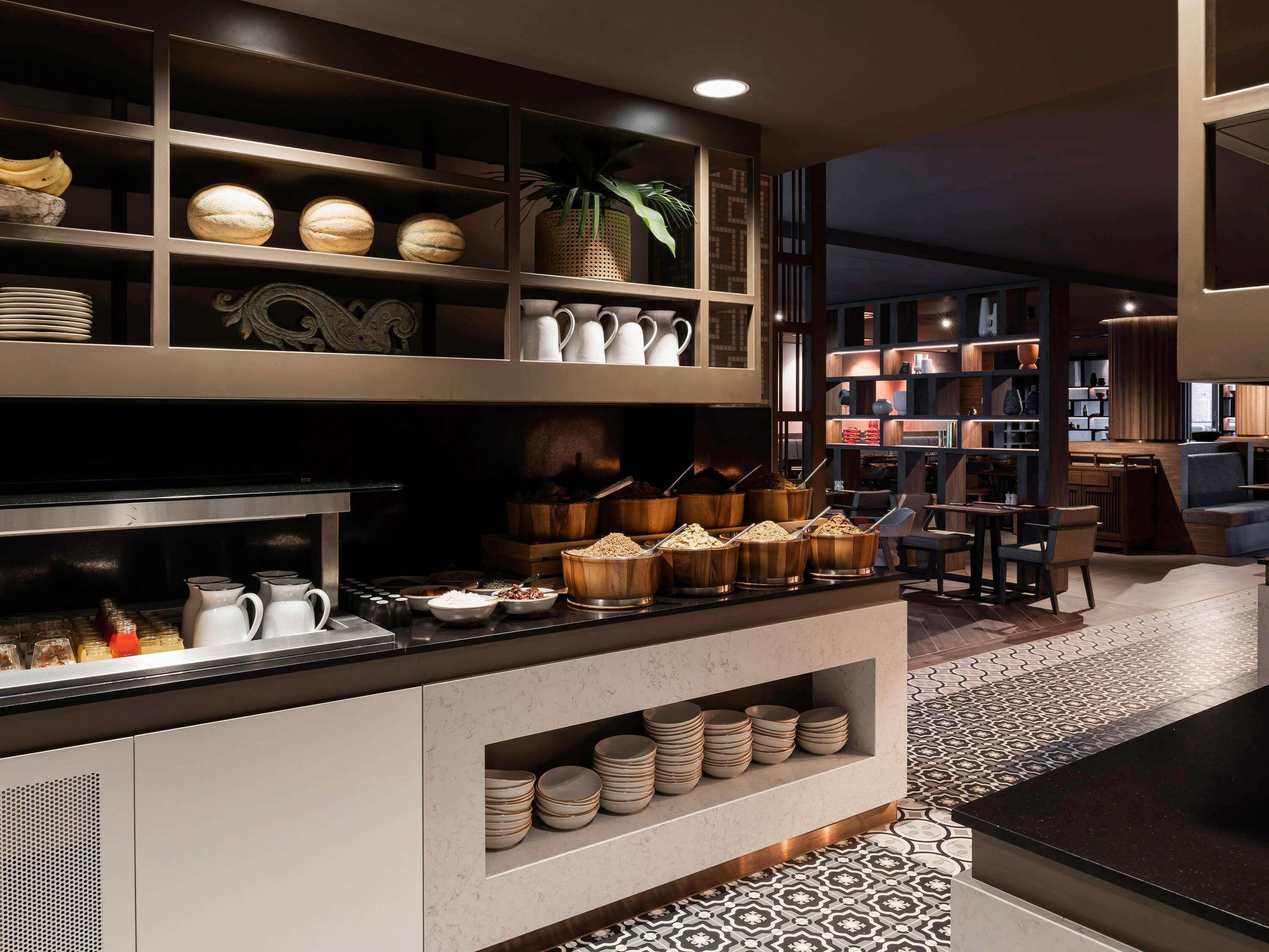 A modern kitchen with built-in shelves, a dining area, and a patterned floor.