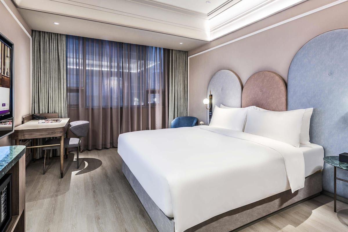 Habitación de hotel con cama, escritorio, silla y televisor.