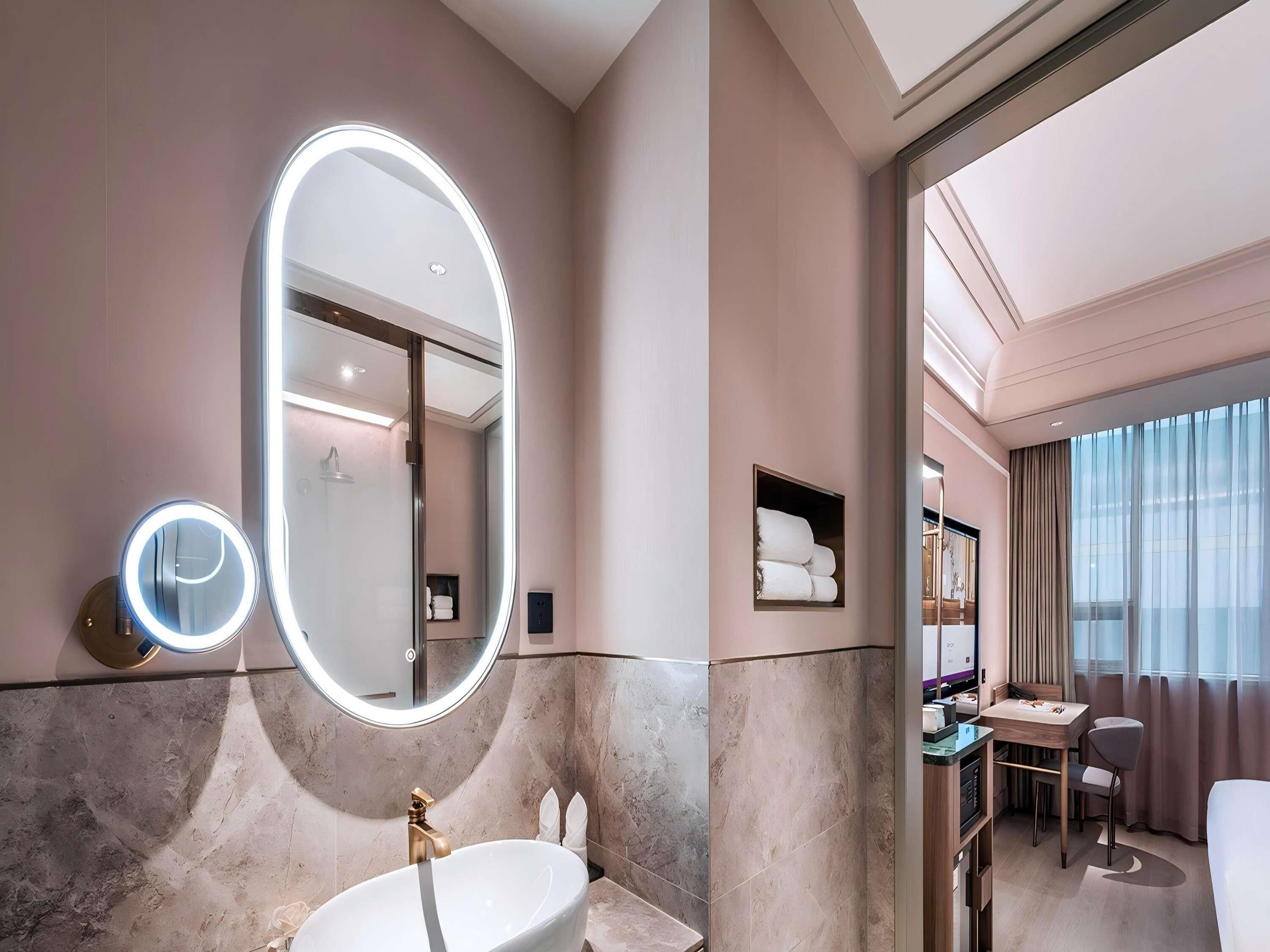 A modern bathroom with a large mirror, vanity, and a separate shower area.