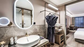 Un baño de hotel moderno con un espejo grande, un lavamanos y un perchero para batas.