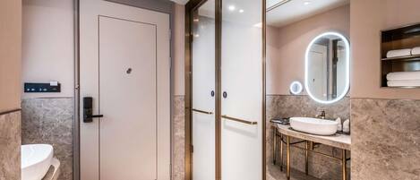 A modern bathroom with a glass door, a vanity with a sink, and a mirror with a light.