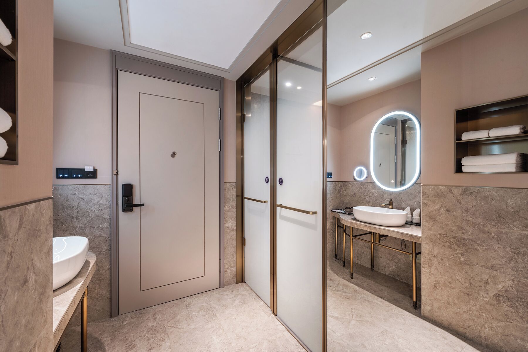 Une salle de bain moderne avec une porte en verre, un meuble-lavabo et un miroir avec éclairage intégré.