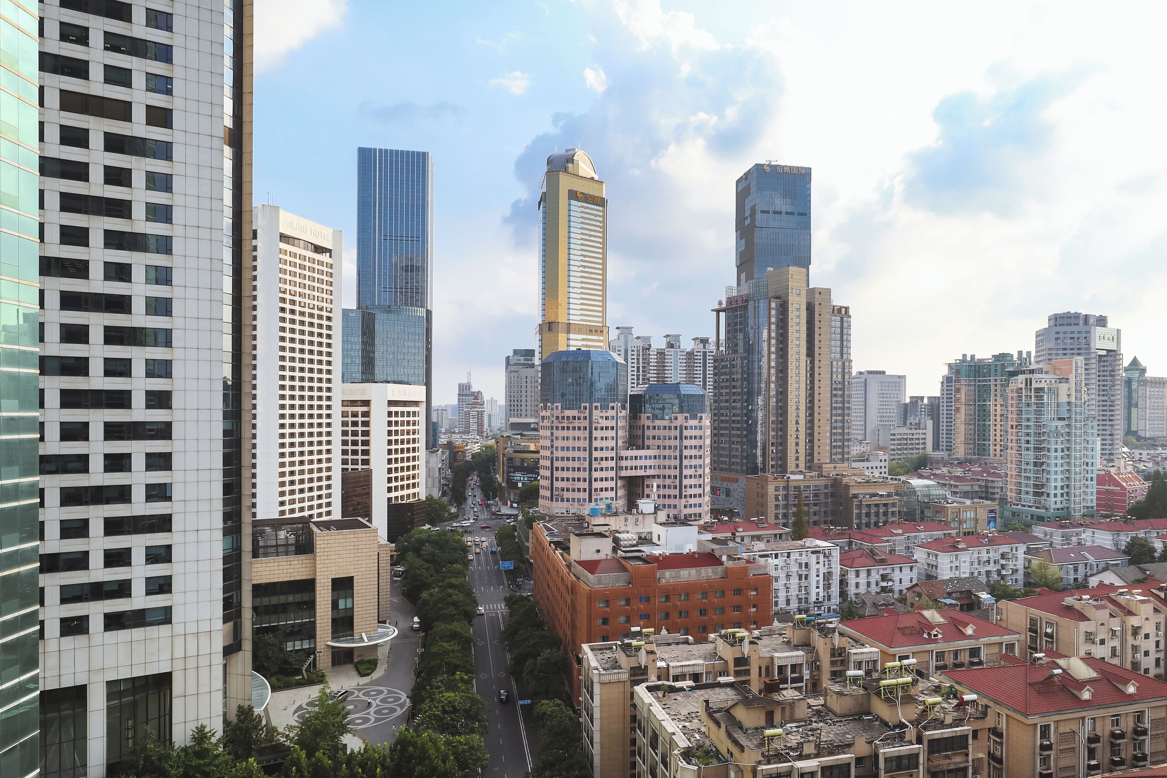 Un paysage urbain avec des immeubles modernes de grande hauteur, un mélange de bâtiments résidentiels et commerciaux, et un ciel dégagé.