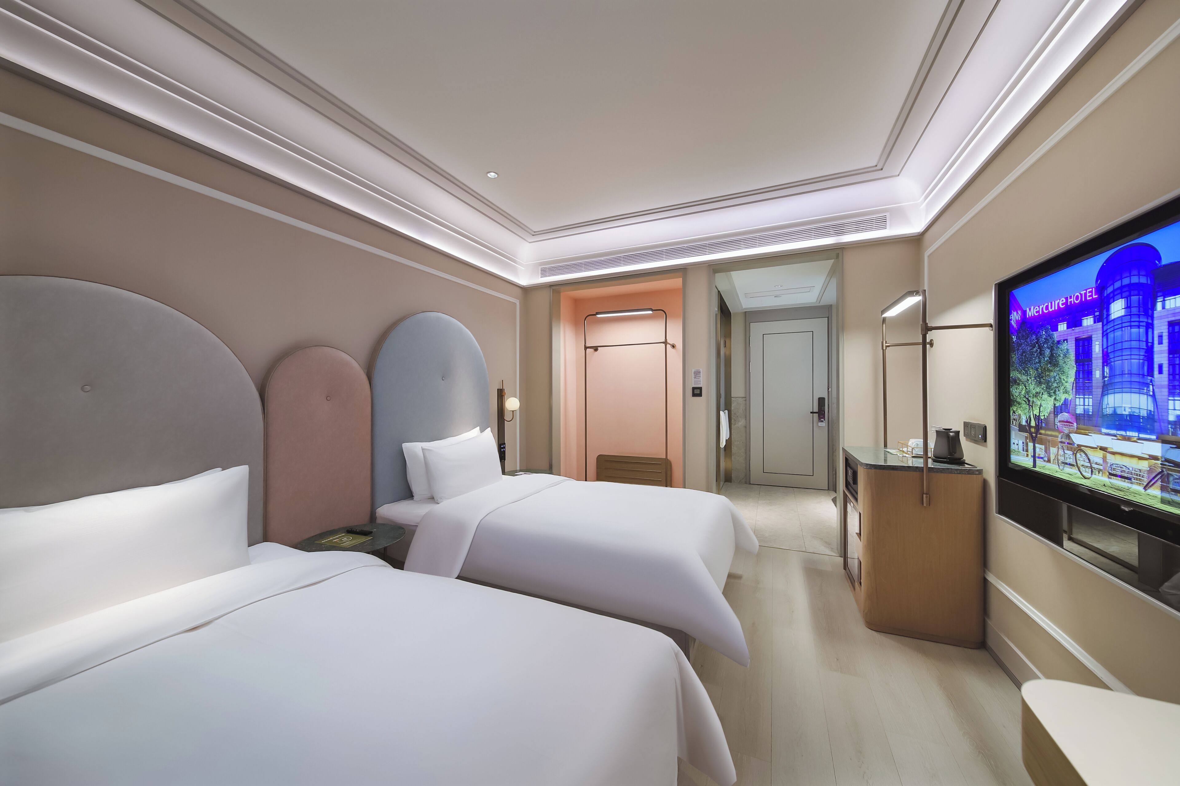 Ein Hotelzimmer mit zwei Betten, einem Fernseher, einem Schreibtisch und einer Badezimmertür.
