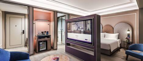 Habitación de hotel con cama, televisión, cafetera, escritorio y sofá.