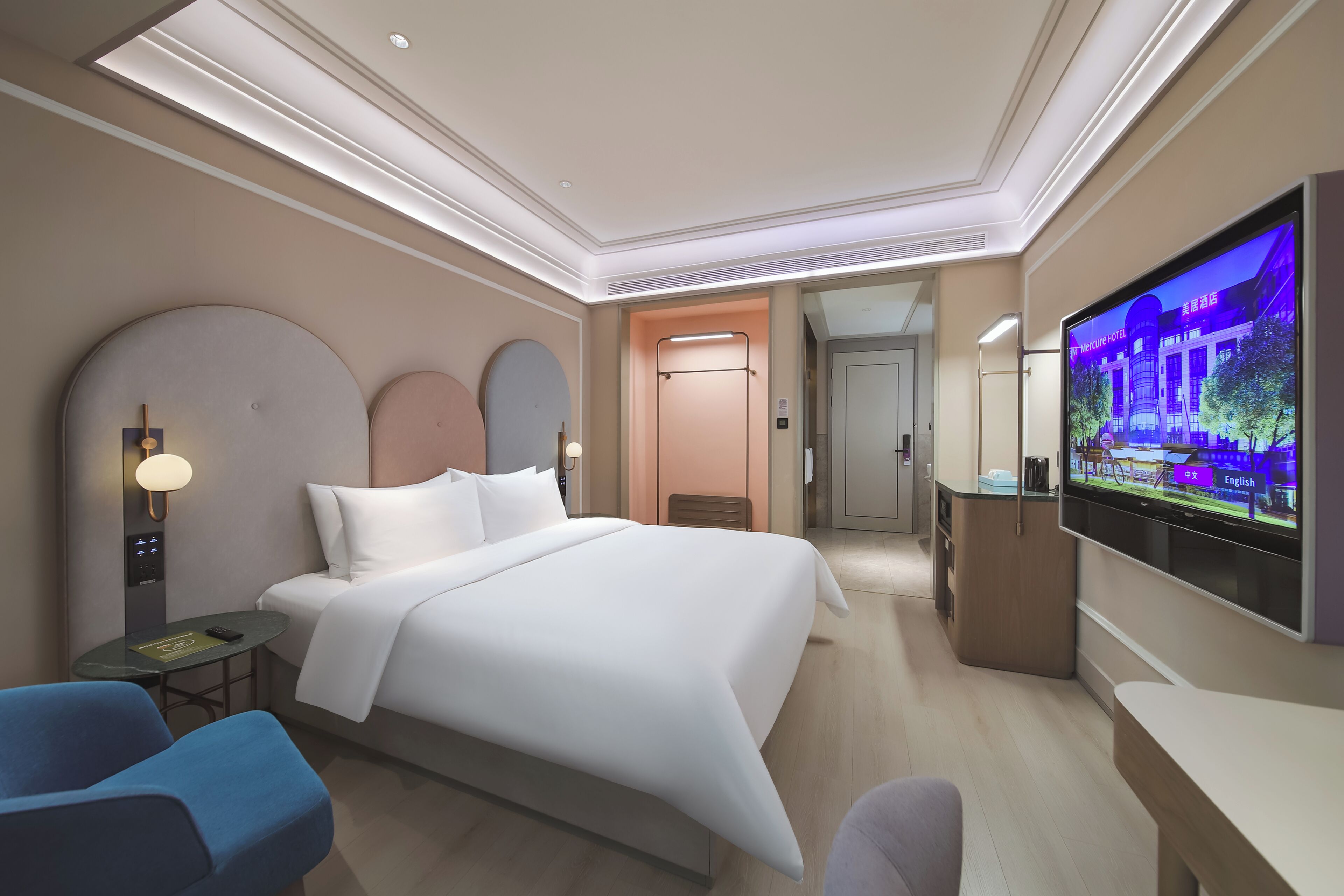 Una habitación de hotel moderna con una cama grande, televisión, escritorio y zona de estar.