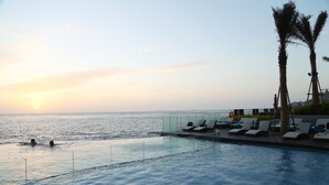 A poolside area with lounge chairs and palm trees, overlooking the ocean at sunset. - Mercure Vung Tau (Ho Chi Minh City)
