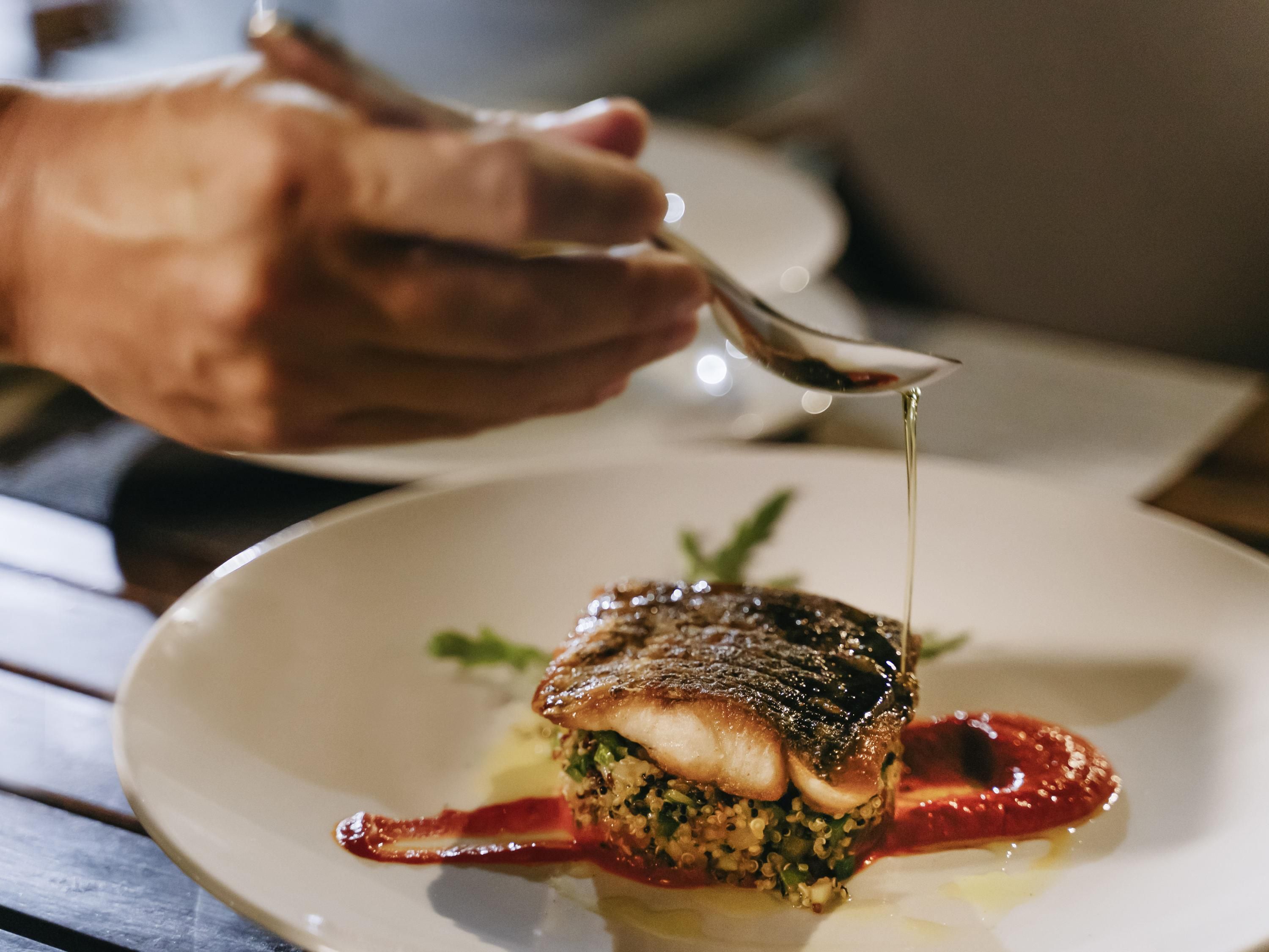 A dish with a sauce being poured onto it.