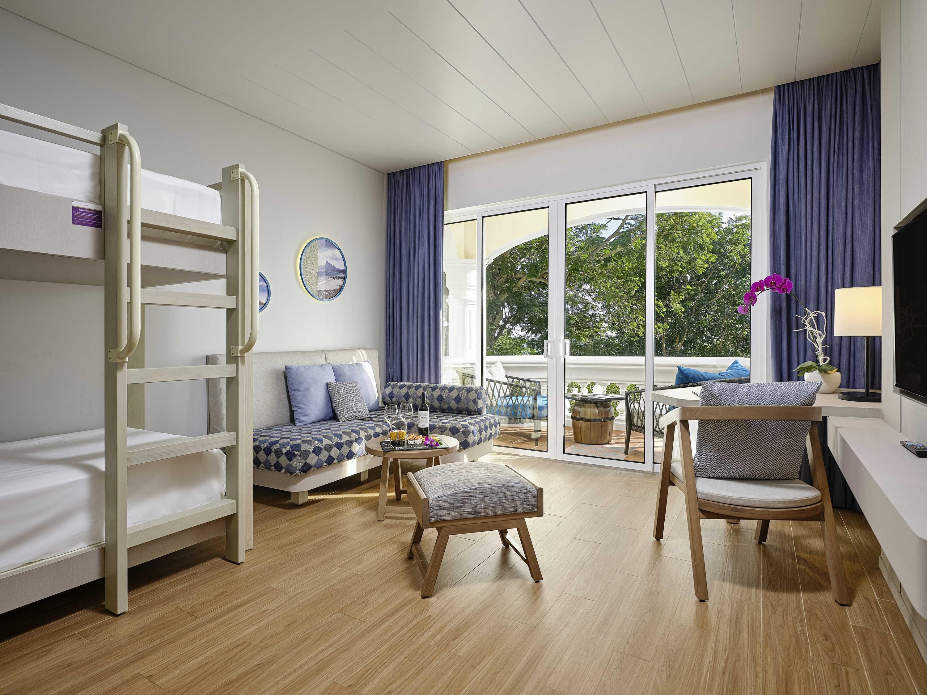 A hotel room with bunk beds, a sofa, a dining table, and a TV.