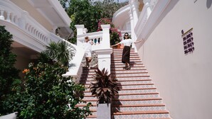A grand staircase with ornate white railings and patterned tiles, surrounded by lush greenery and decorative plants. - Mercure Vung Tau (Ho Chi Minh City)