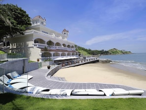 A resort with a beach view, a pool area with lounge chairs, and a building with a balcony.