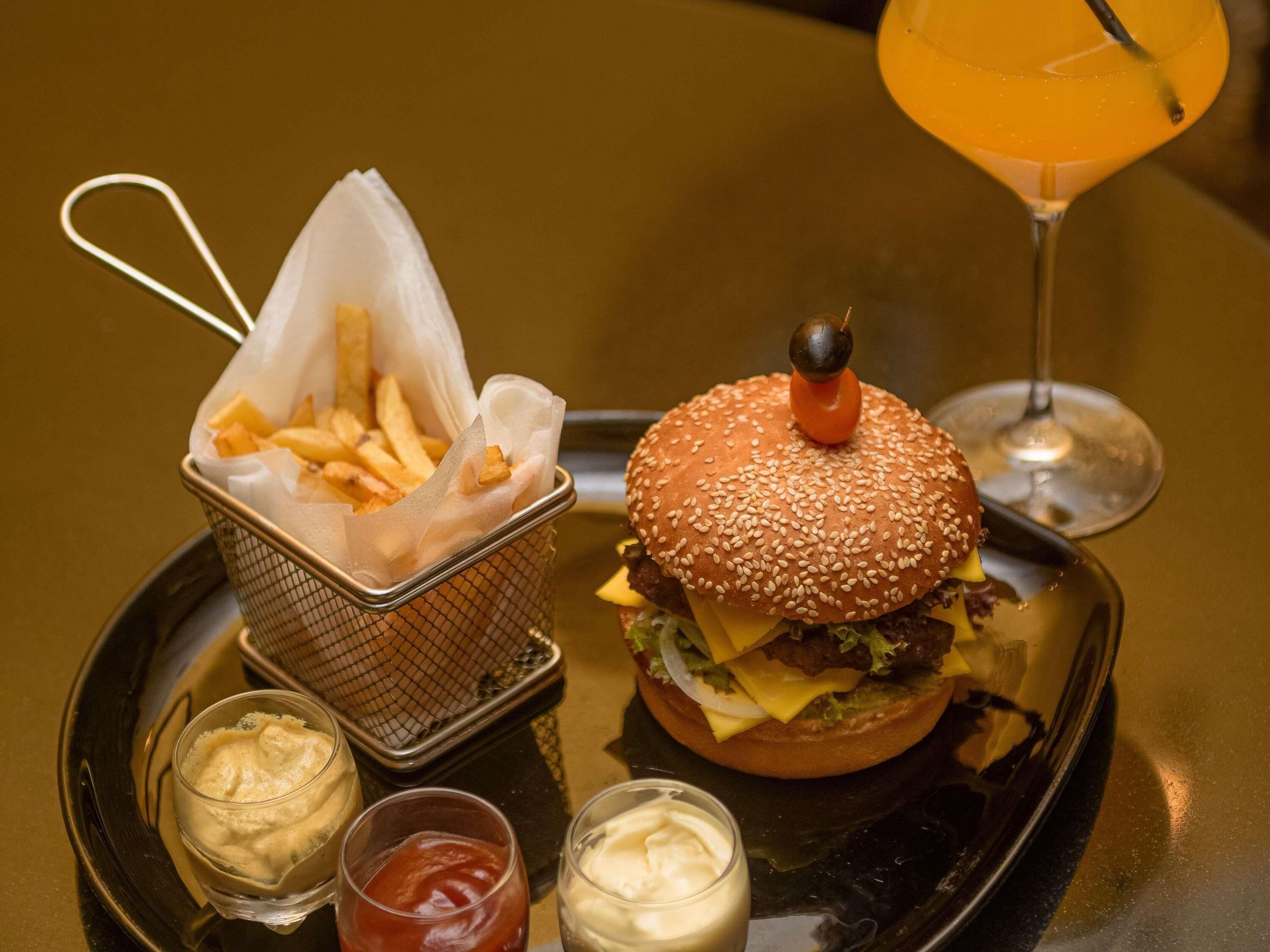 A tray with a burger, fries, and condiments.