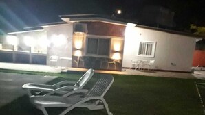 A modern building with a well-maintained lawn and a lounge chair.