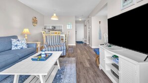 Een woonkamer met een bank, salontafel, tv-meubel en een eethoek met stoelen en een tafel.