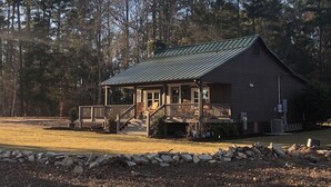 Eine Lodge mit überdachter Veranda, Steinwand und Metalldach.