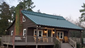 Ein Haus mit überdachter Veranda, einer Holzterrasse und einem Ziegelkamin.