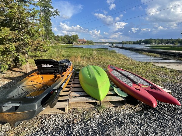 A row of kayaks and a motorboat on a wooden dock by a calm body of water. - THE CABIN AT HIDDEN COVE (Chapin)