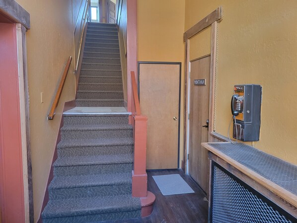 A staircase with carpeted steps, a wooden handrail, and a door labeled "MONTANA". - Dillon Tap House Sweetwater Room (Dillon)
