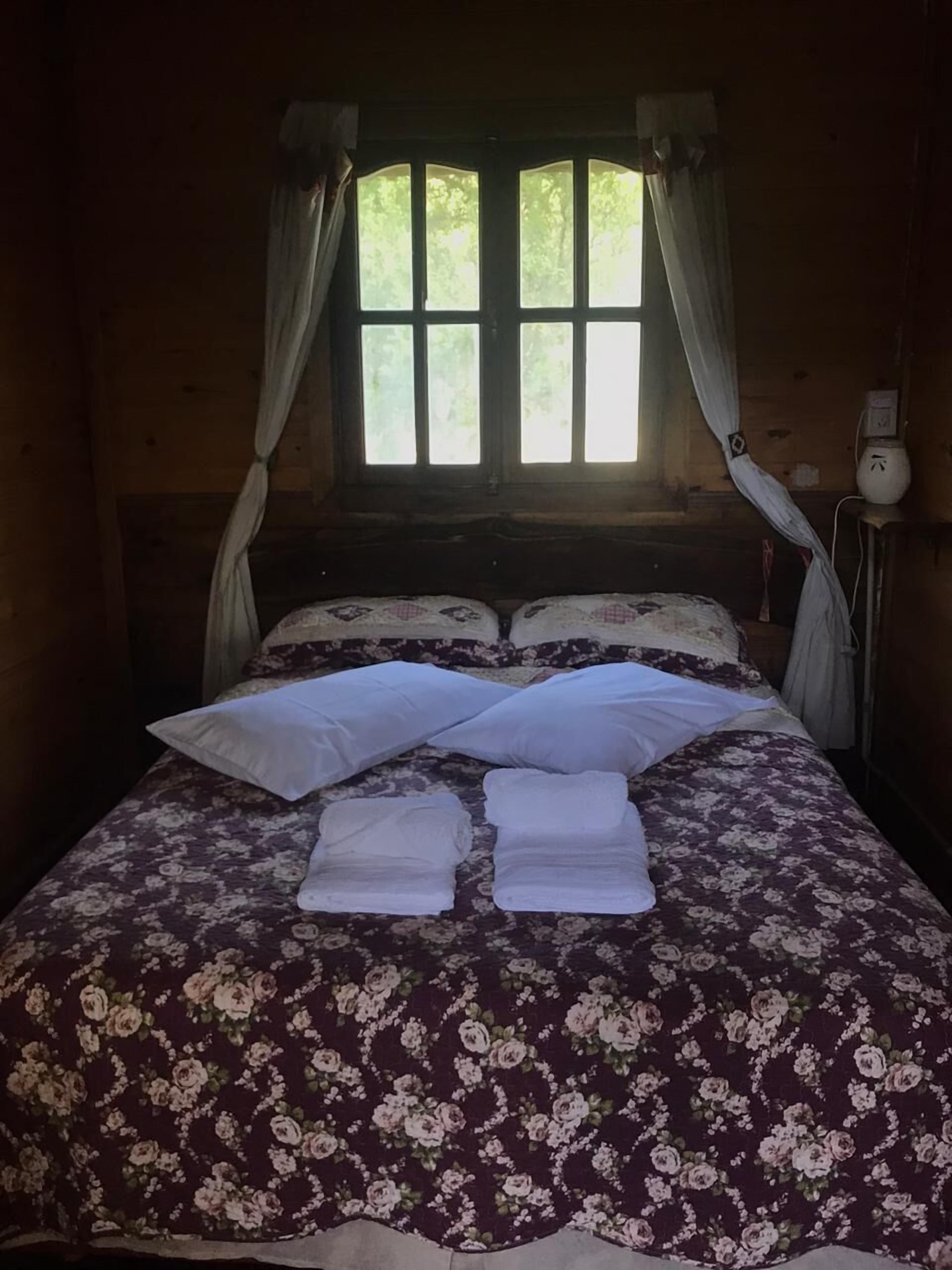 Un letto con copriletto floreale, due cuscini e due asciugamani piegati.
