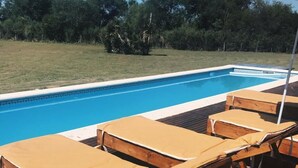 Una terraza de madera con sillones de descanso y una piscina.