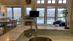 Eine Küche mit Spüle, Essbereich und großen Fenstern mit Blick auf ein Gewässer.