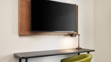 A modern room with a mounted flat-screen TV, a desk, and a green chair.