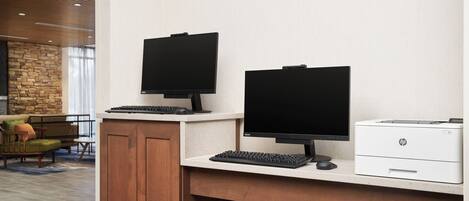 A modern office desk with two monitors, a keyboard, and an HP printer.
