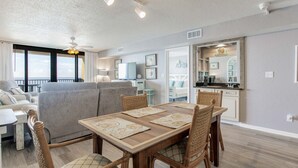 Un salon moderne comprenant un canapé, une table à manger et des chaises. Il y a également un coin cuisine avec des placards et un plan de travail.