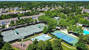 Zona residencial con varias casas, una cancha de tenis grande y una piscina.