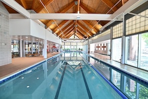 Une piscine intérieure dotée d’un plafond haut, de grandes fenêtres et d’un sol carrelé.