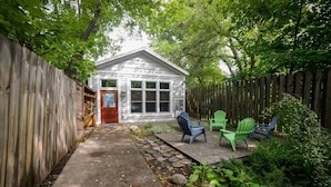 A small house with a front door, a porch with four Adirondack chairs, and a stone pathway leading to the door. - Second Street Stay–Downtown+ WALKABLE TO CHERRY FEST (Traverse City)