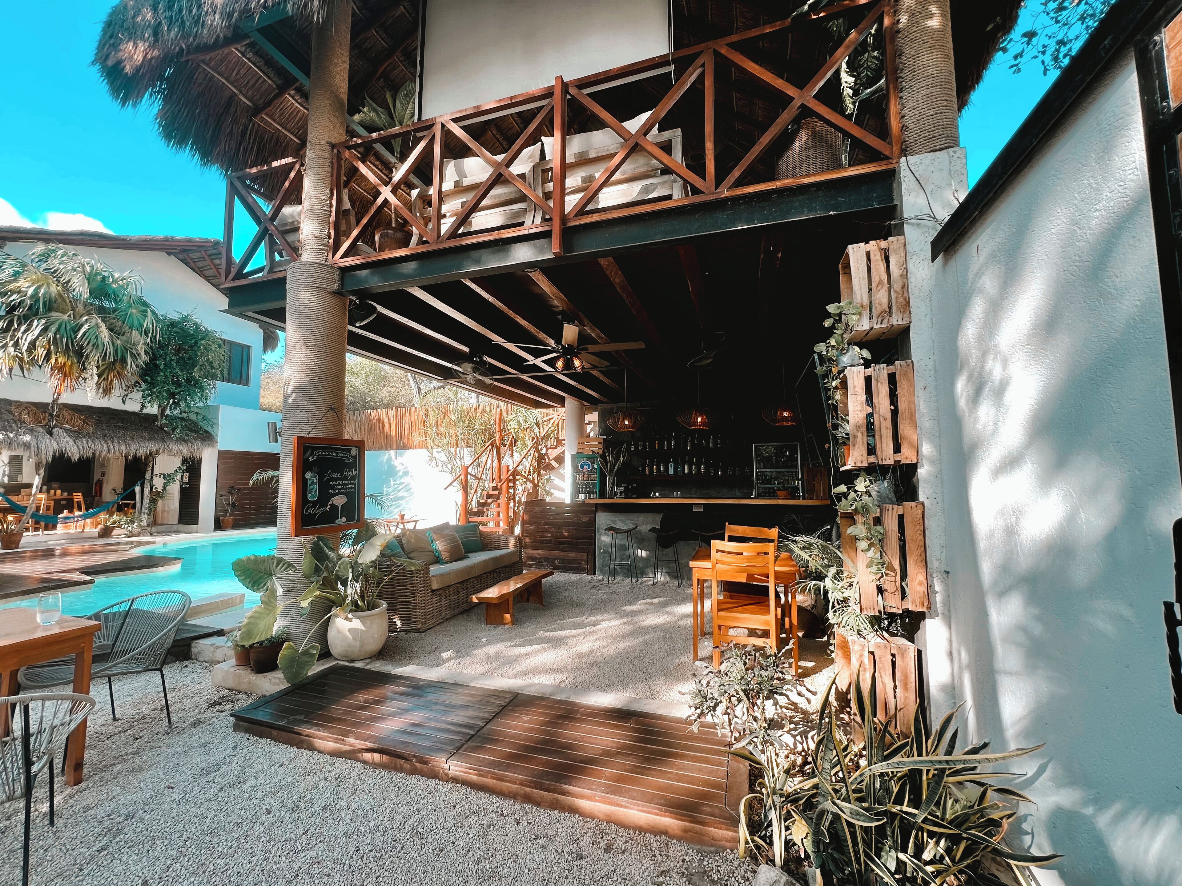 An outdoor pool area with seating, a bar, and a staircase leading to an upper deck.