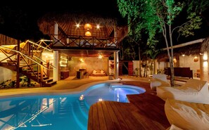 A pool area with a wooden deck, a thatched-roof structure, and a seating area with cushions. - Mimosa Tulum Hotel & Hostel (Tulum)