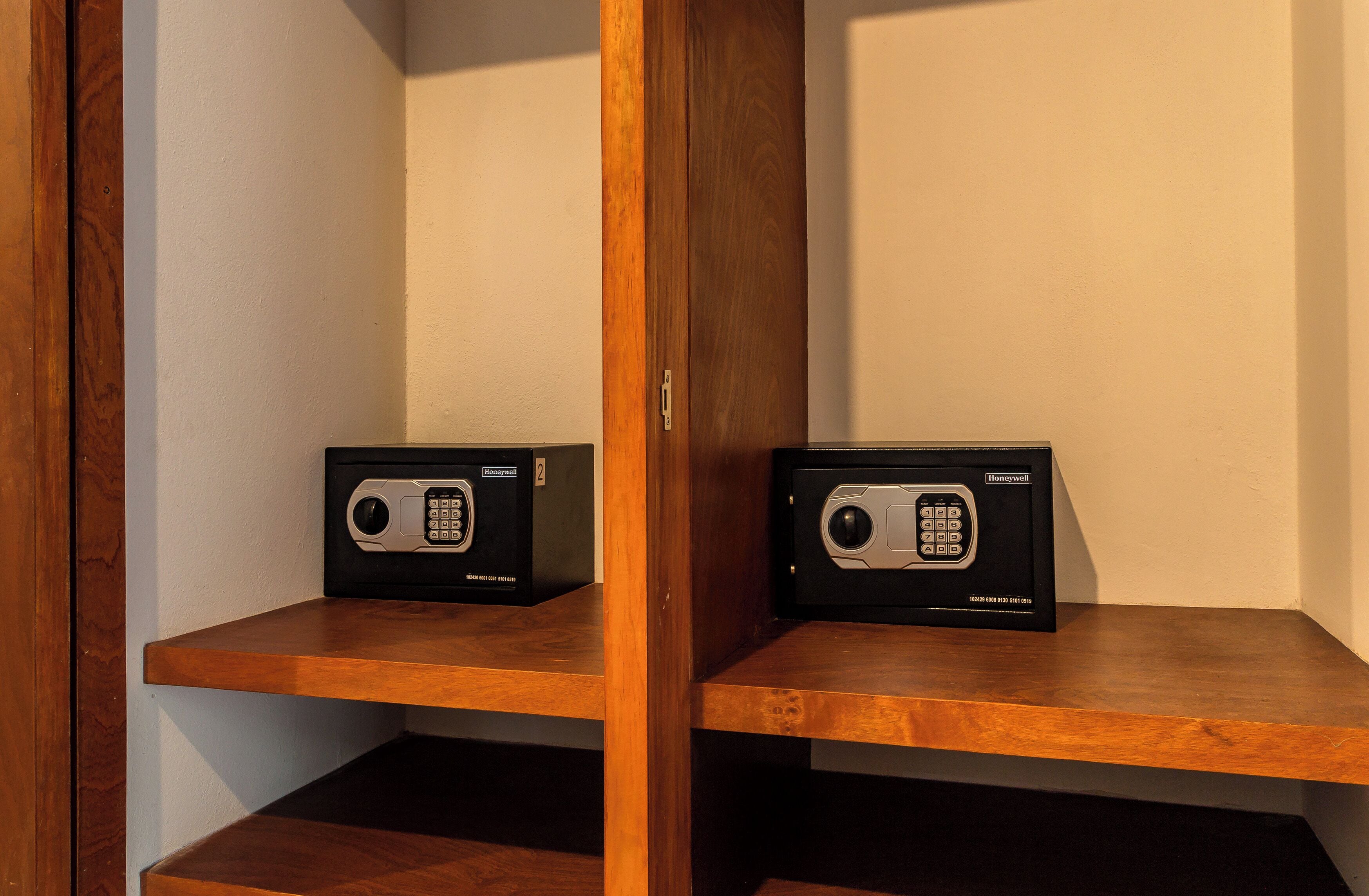 Two safes on wooden shelves against a wall.