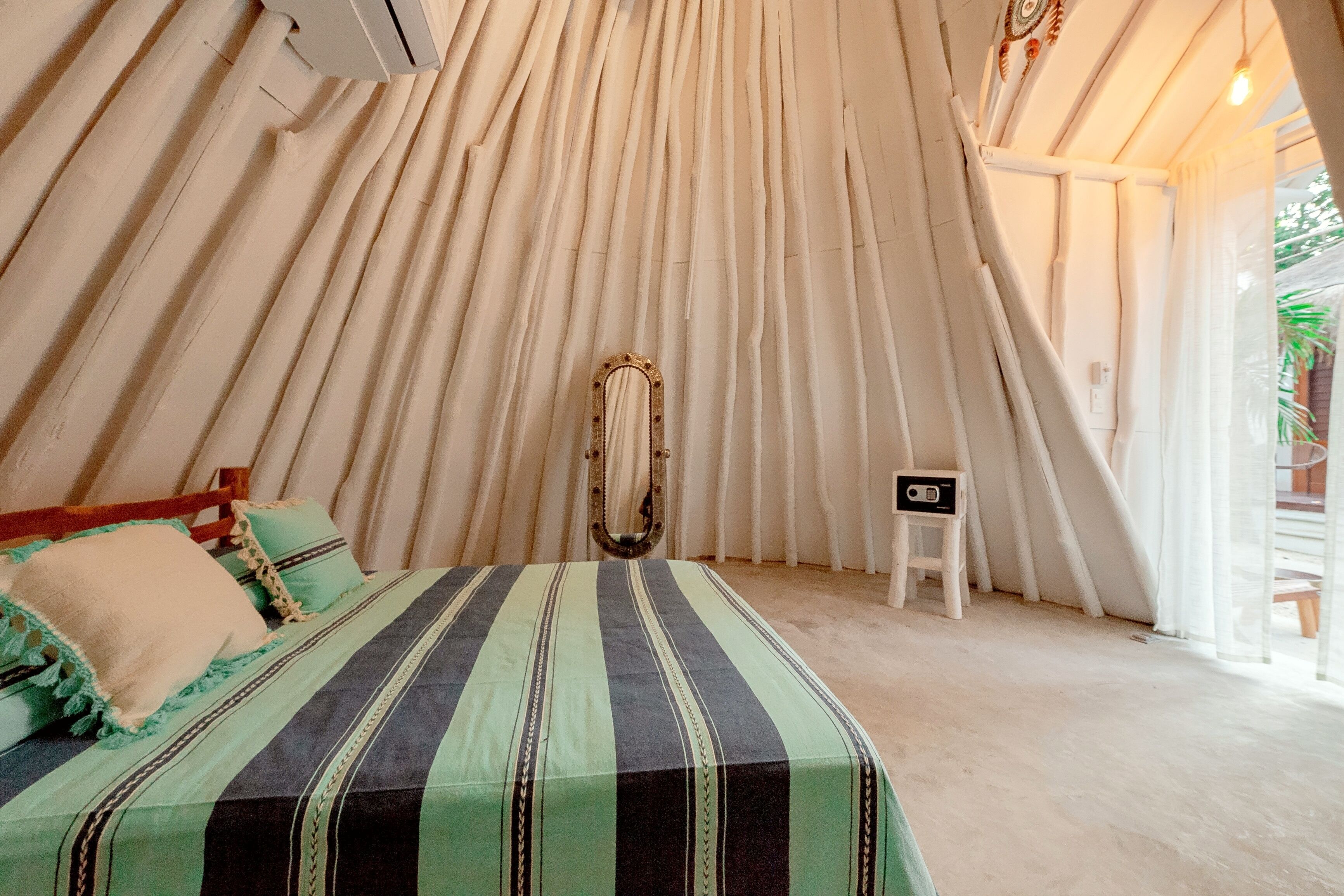 A tent-style room with a bed, a small stool, and a radio.