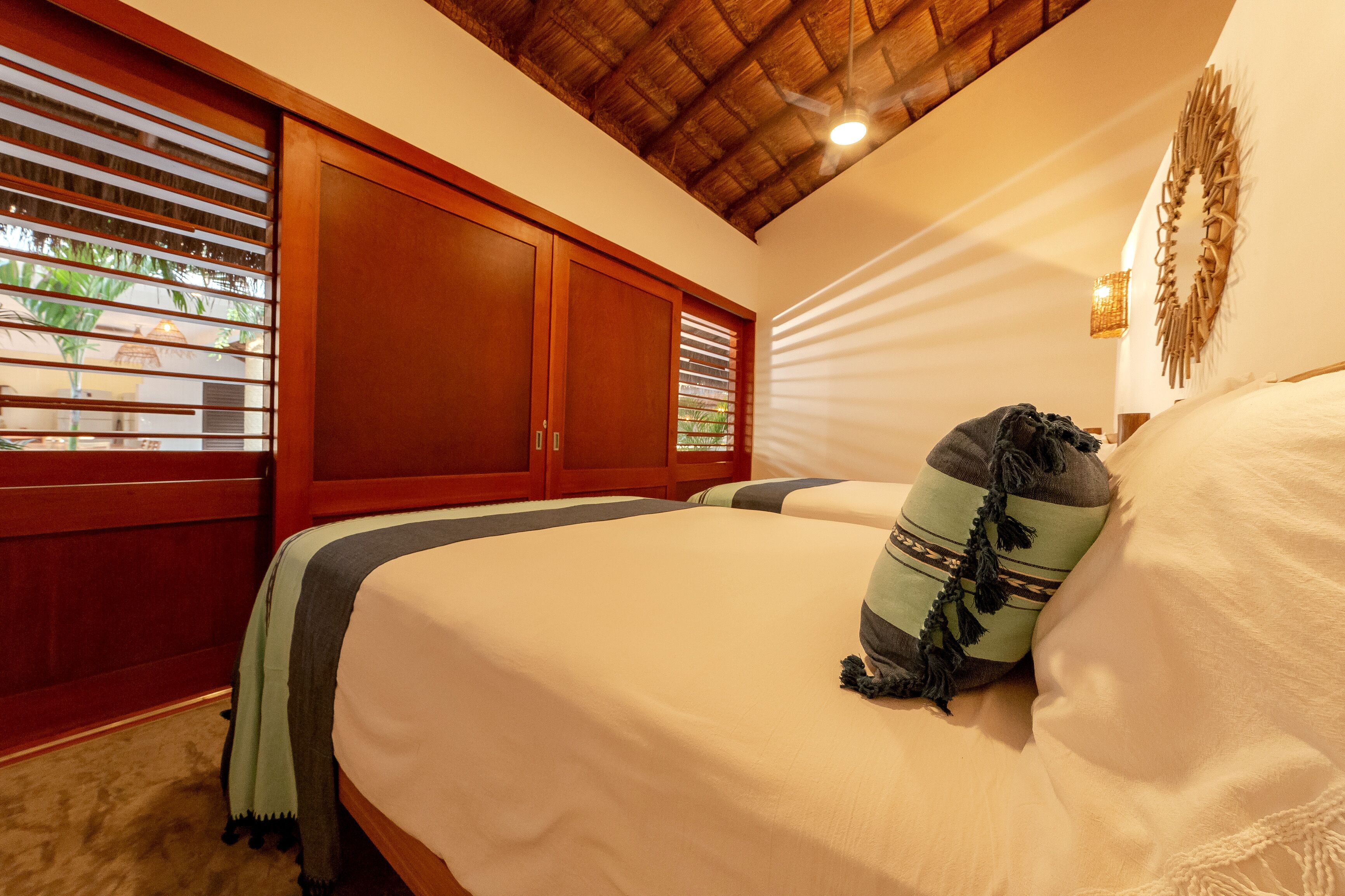 A bedroom with a bed, wooden wardrobe, and a ceiling fan.