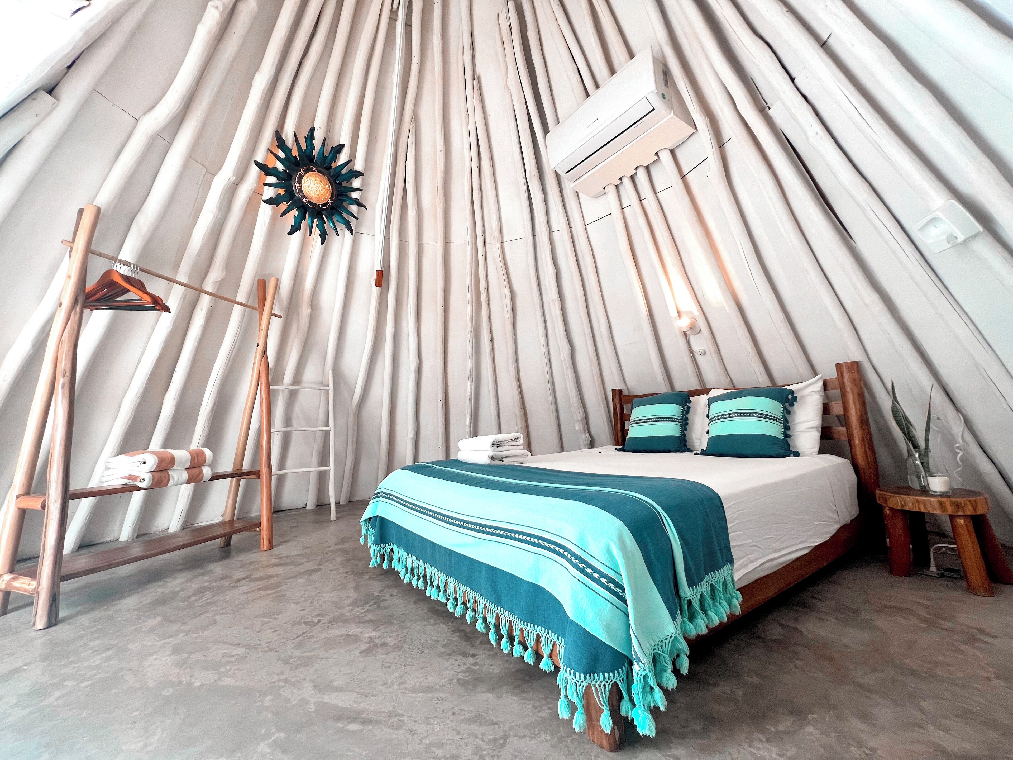 A cozy, tent-like room with a bed, a hanging light fixture, and an air conditioning unit.