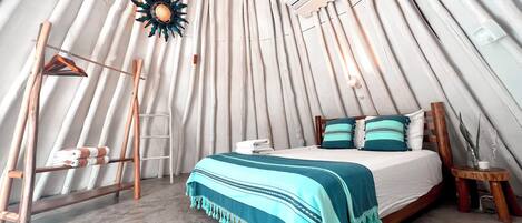 A cozy, tent-like room with a bed, a hanging light fixture, and an air conditioning unit.