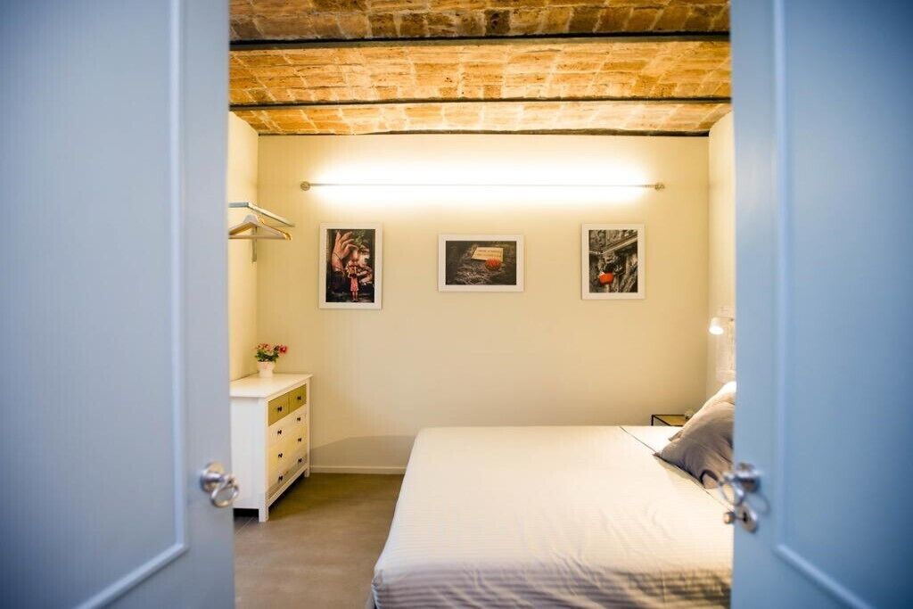 Una camera da letto con un letto, una cassettiera e tre quadri appesi al muro.