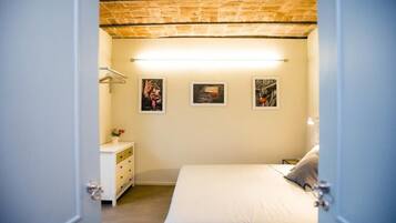 Una camera da letto con un letto, una cassettiera e tre quadri appesi al muro.